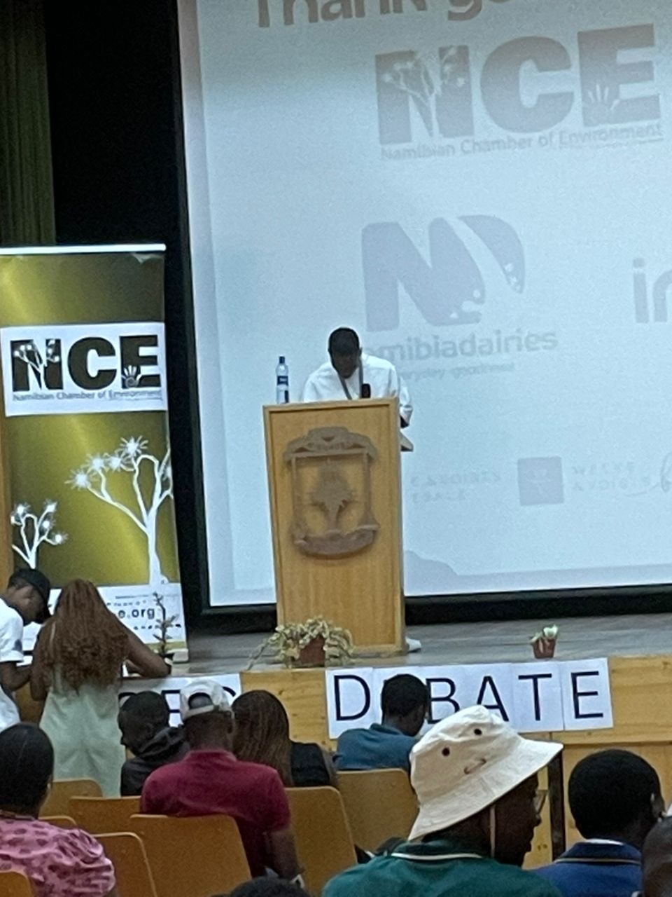A speaker thanking NCE and sponsors from the podium at the High Schools Environmental Debate