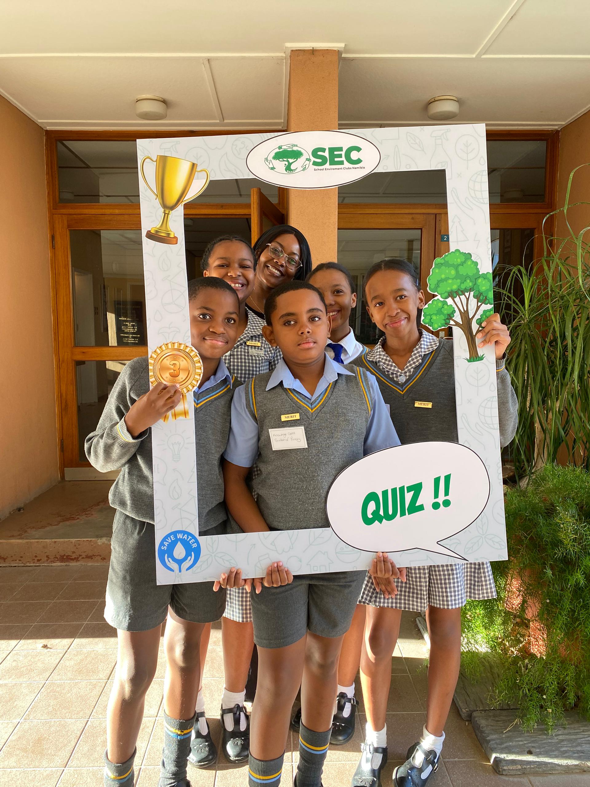 Learners and a teacher posing with the SEC Quiz photo frame