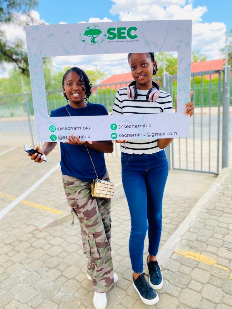 Two learners holding the SEC Namibia social media photo frame